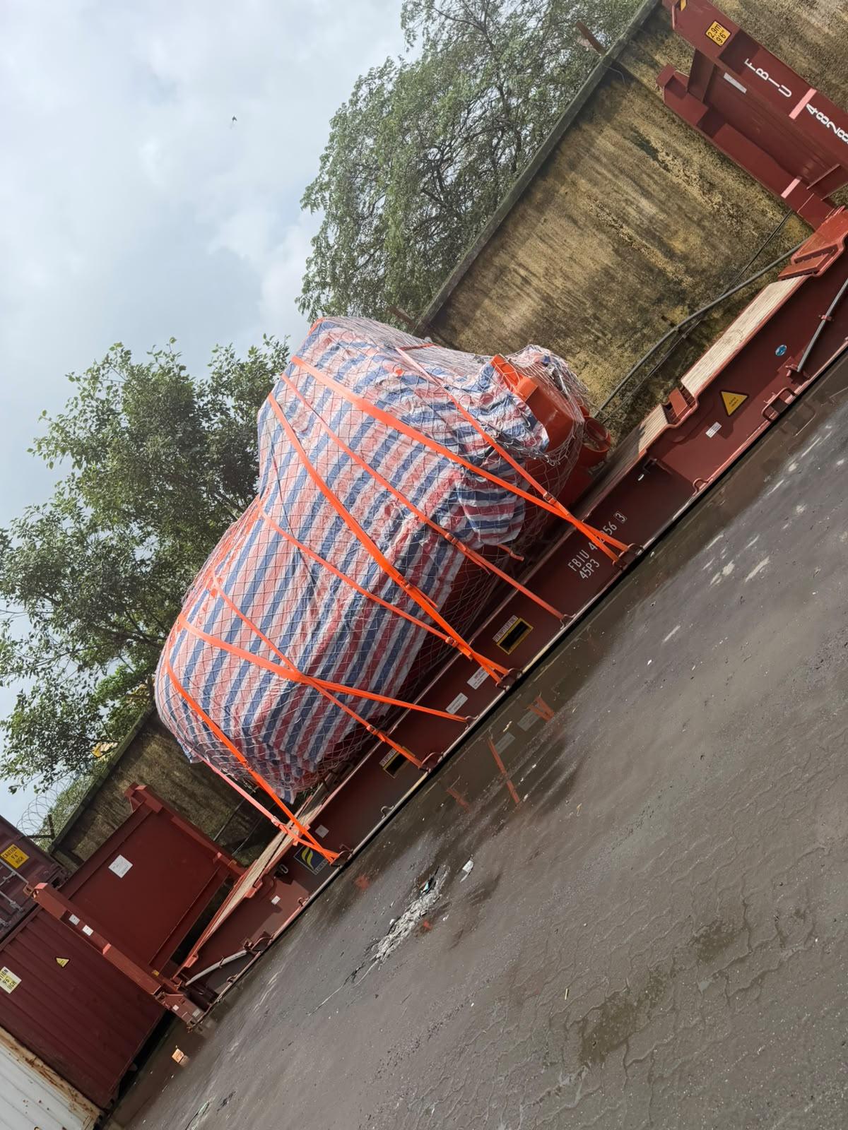 Shrink-wrapped project cargo strapped to a flat rack